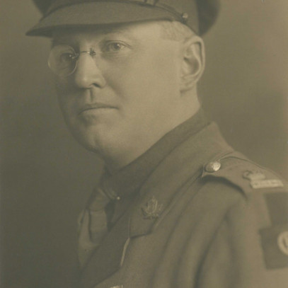 Black and white photograph. MacGillivray is shown from the chest up in military uniform. The photo nearly shows a side profile, and so his Canada badge and service decorations worn on the left side of his body are visible.