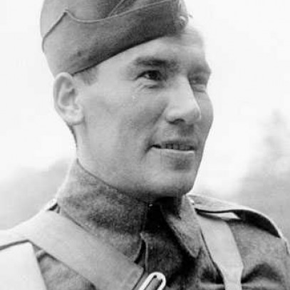 Black and white photograph. Harvey Dreaver looks into the distance, shown from the chest up. He is in full uniform, including a cap. There is a strap across his chest.