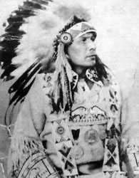 Black and white portrait. Chief Joseph Dreaver of the Mistawasis Band is shown in full regalia, including headdress and traditional dress.