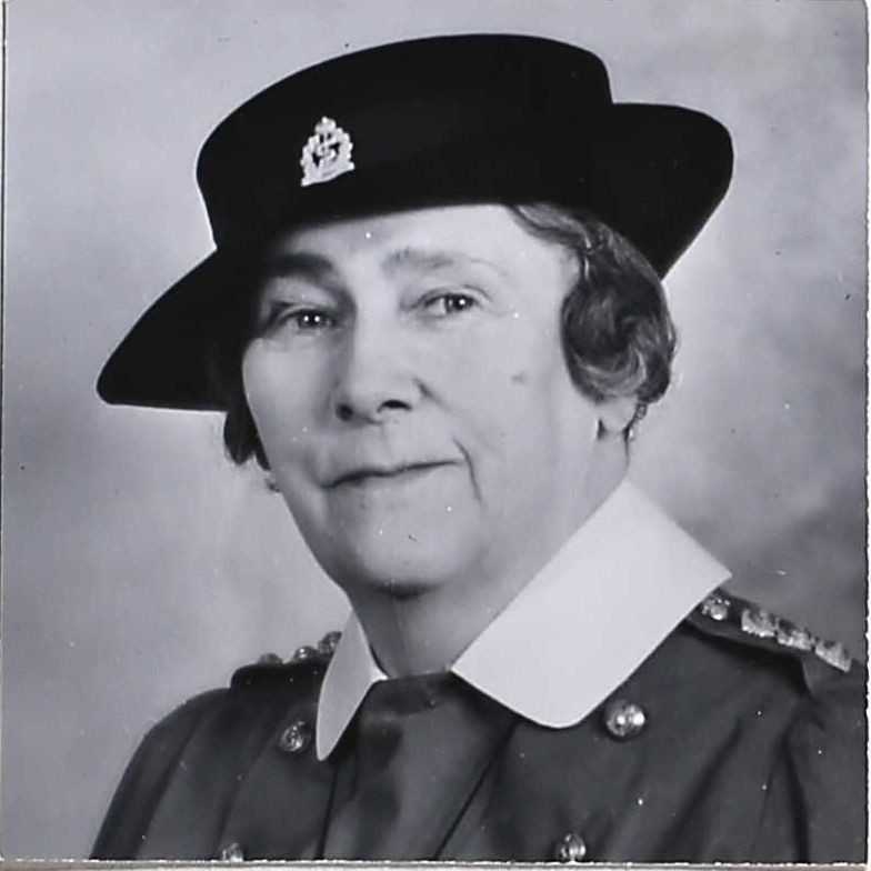 A black and white headshot of Nellie in her Second World War uniform. She is wearing a short wide-brimmed hat, and her sharp white collar sits on top of her military jacket. Emblems are visible on the hat and on her shoulders.